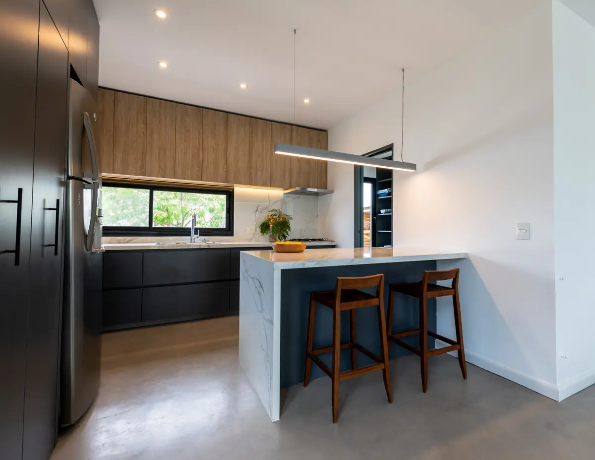 Cozinha moderna com ilha de mármore e madeira natural — projeto Santa Isabel - Andrea Gonzalez, por ABEJA CONCEPT, em Nordelta