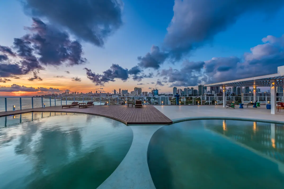 Área de piscina infinita ao pôr do sol com vista para a cidade — projeto Novotel, Salvador, por Mauricio Moreno Fotografia