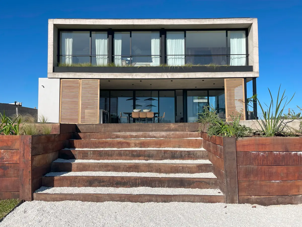 Fachada moderna com revestimento de madeira e grandes janelas — projeto El Secreto, por Grupo Pauta Arquitectura, em Tigre