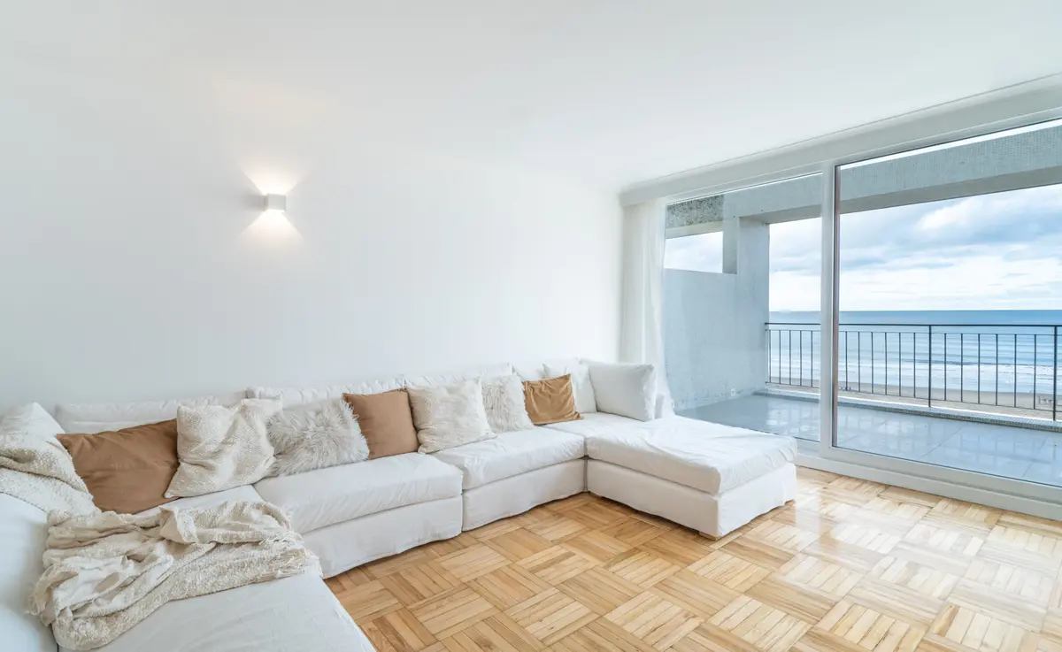 Sala com vista para o mar, sofá branco e piso de madeira — projeto TERRAZA PALACE, por Maria Menna Arquitecta, em Mar del Plata