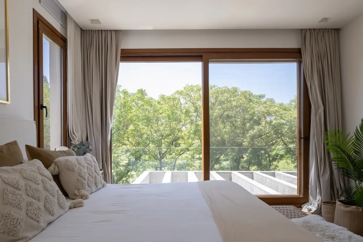 Dormitorio moderno con vista al bosque y grandes ventanales — proyecto Casa BaCa, por Pedro Busso Arq, en Benavidez