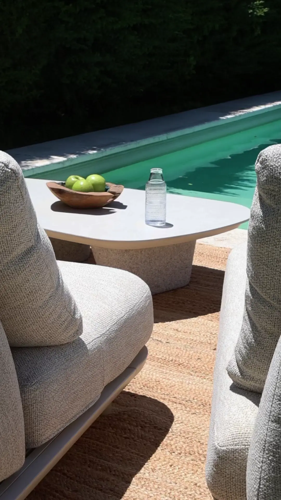 Sala de estar exterior moderna con sillones grises junto a la piscina — proyecto Videos, por Gaby Alfonso, en Buenos Aires